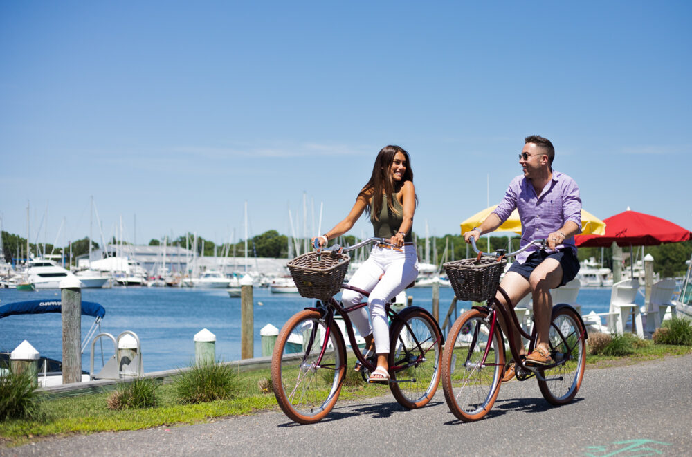 A couple riding bikes by the water.