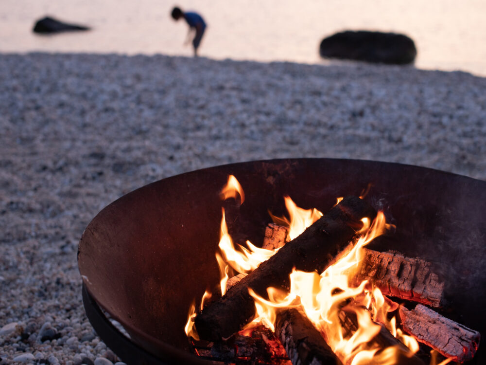 A fire blazing in a fire pit by the beach.