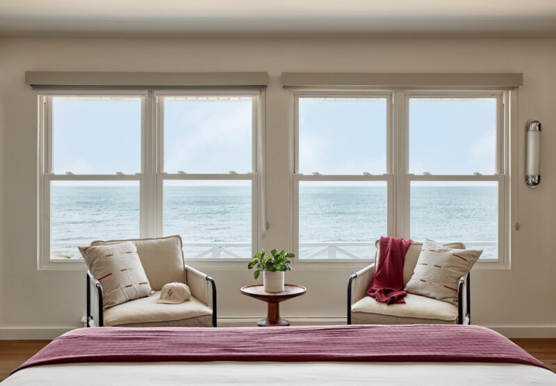 A view of the sound through windows of room, with chairs at the foot of the bed.