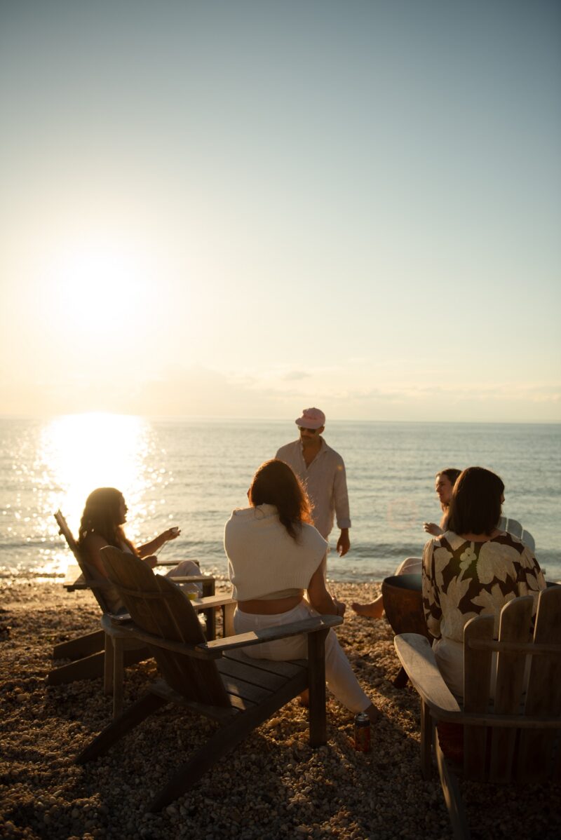 Friends surrounding a fire pit at sunset.