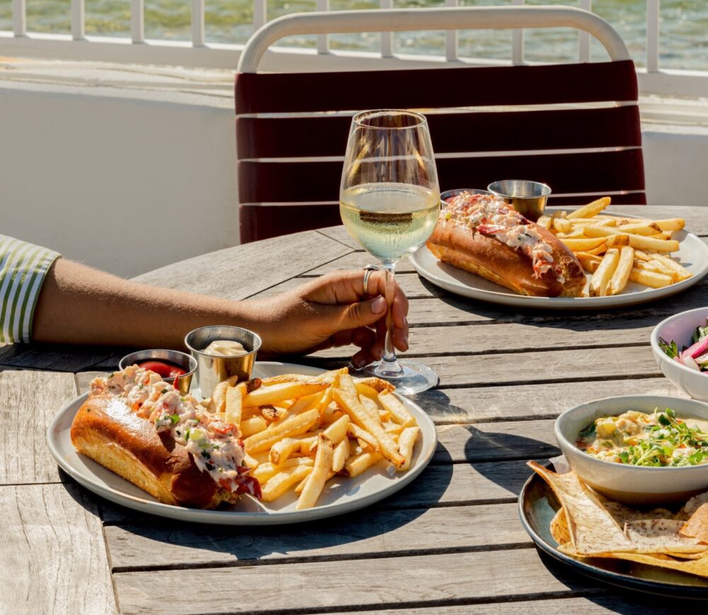 Lobster rolls on a teak table with seaside views.