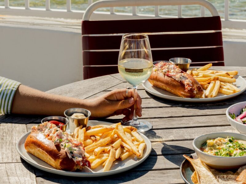 Lobster rolls on a teak table with seaside views.