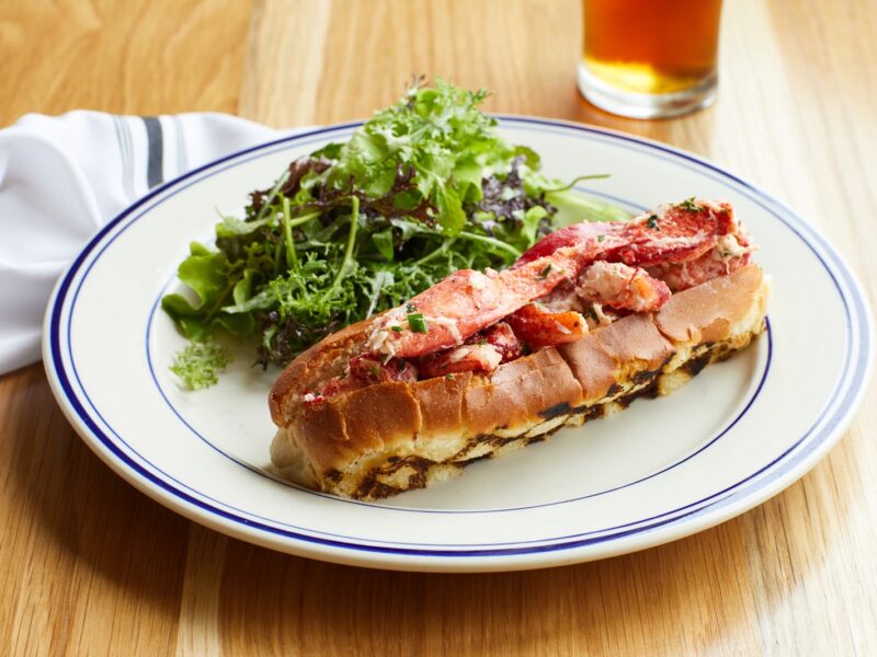 A lobster roll with a bitter green salad and a cold beer.