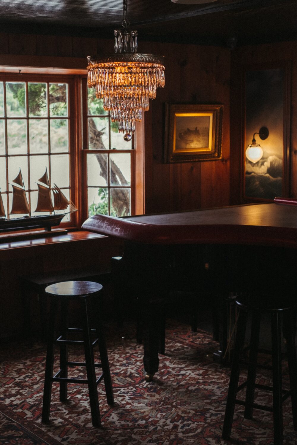 A moody piano bar with a crystal chandelier hanging over the piano.