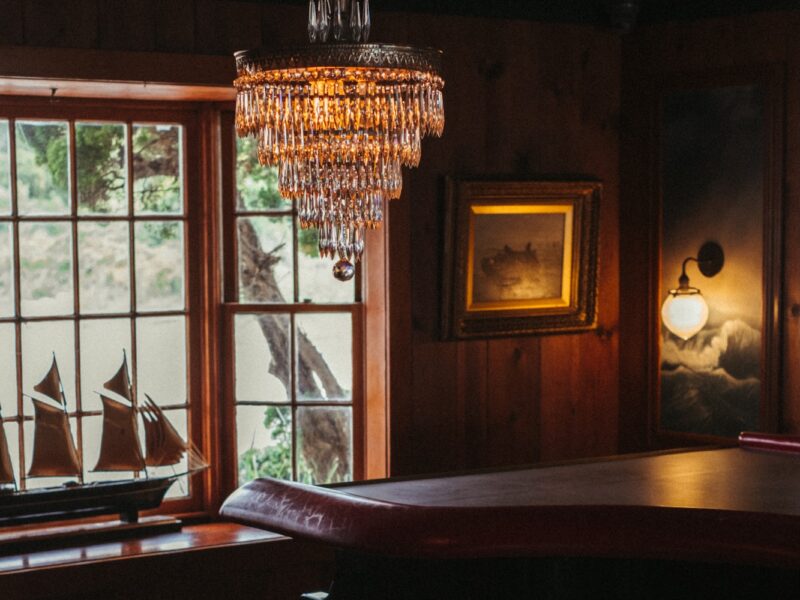 A moody piano bar with a crystal chandelier hanging over the piano.
