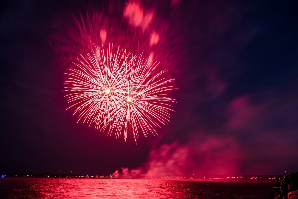 Red and pink fireworks over the bay at Orient Harbor in New York.