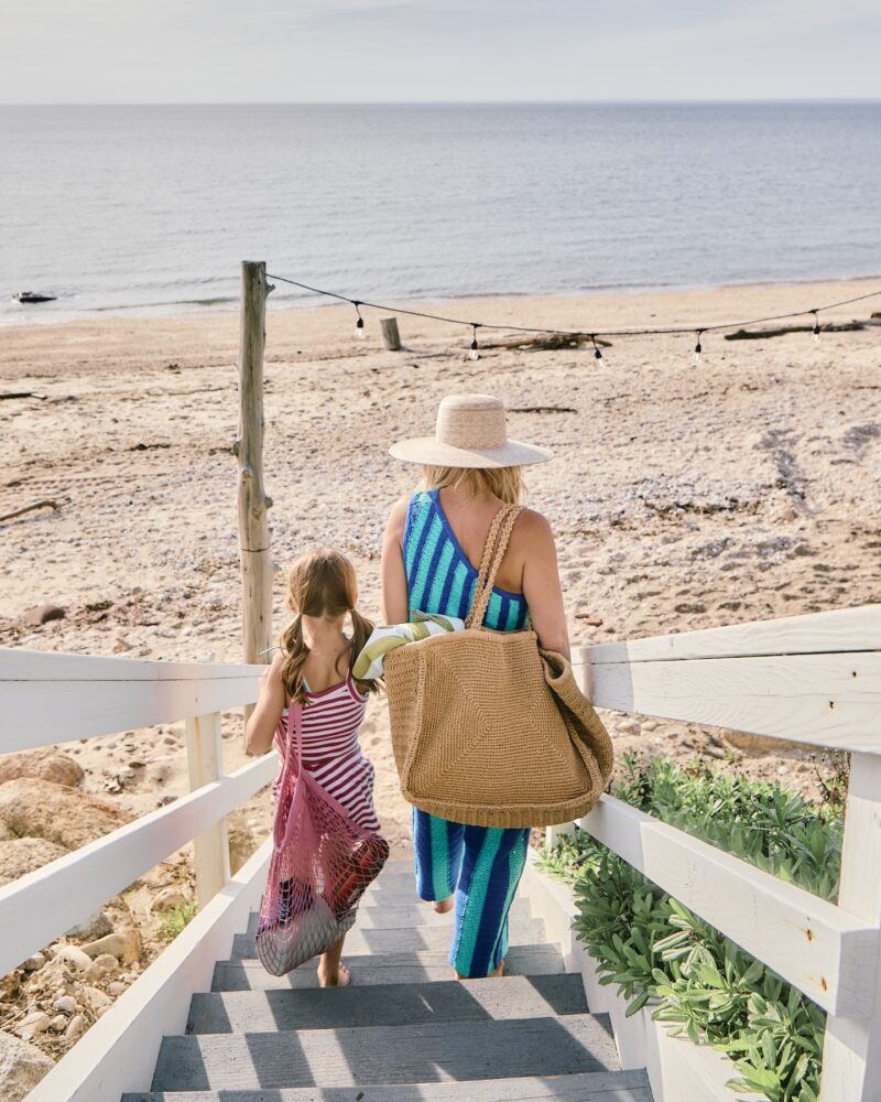 A mother and daughter walking down to the beach.