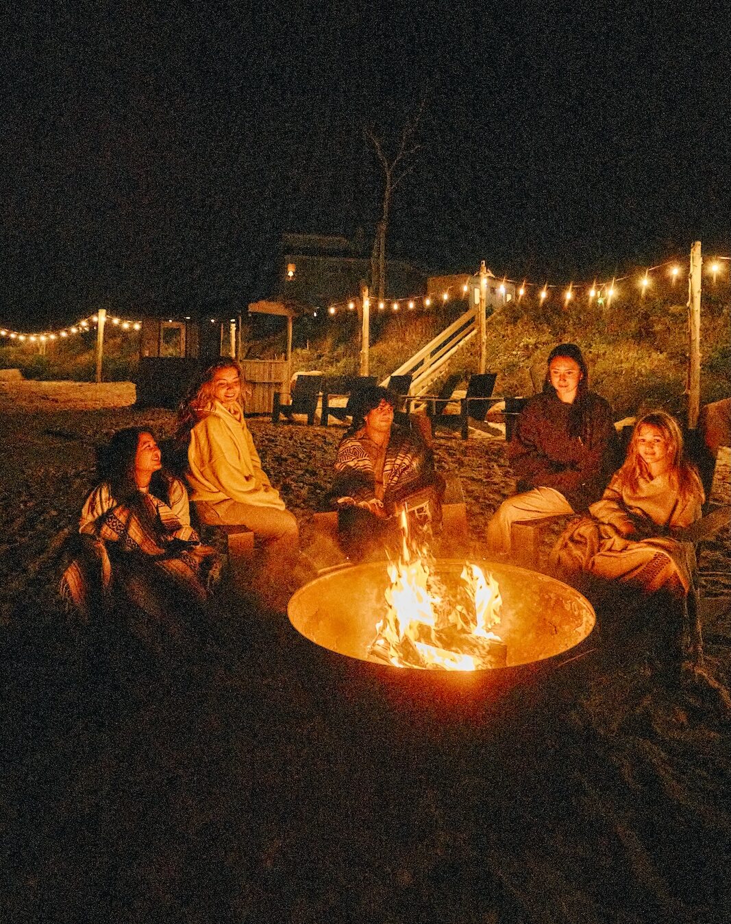 Friends gathered around a fire pit at night.