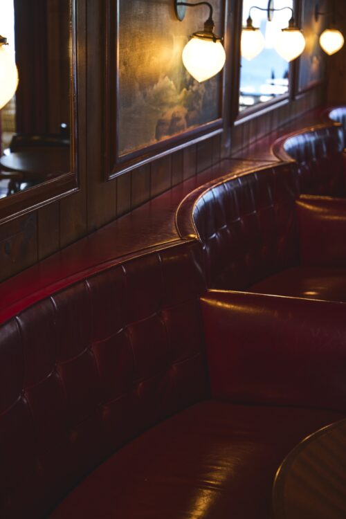 The red leather booths in The Piano Bar, with moody lighting.