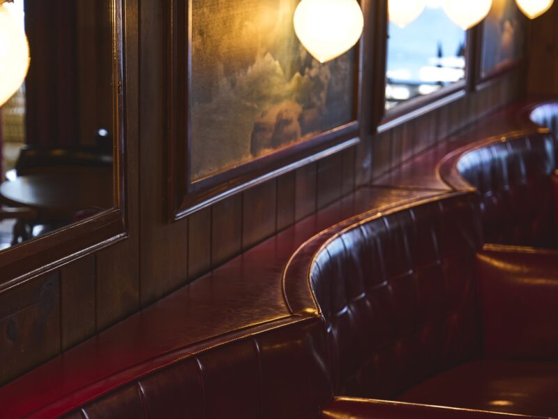 The red leather booths in The Piano Bar, with moody lighting.