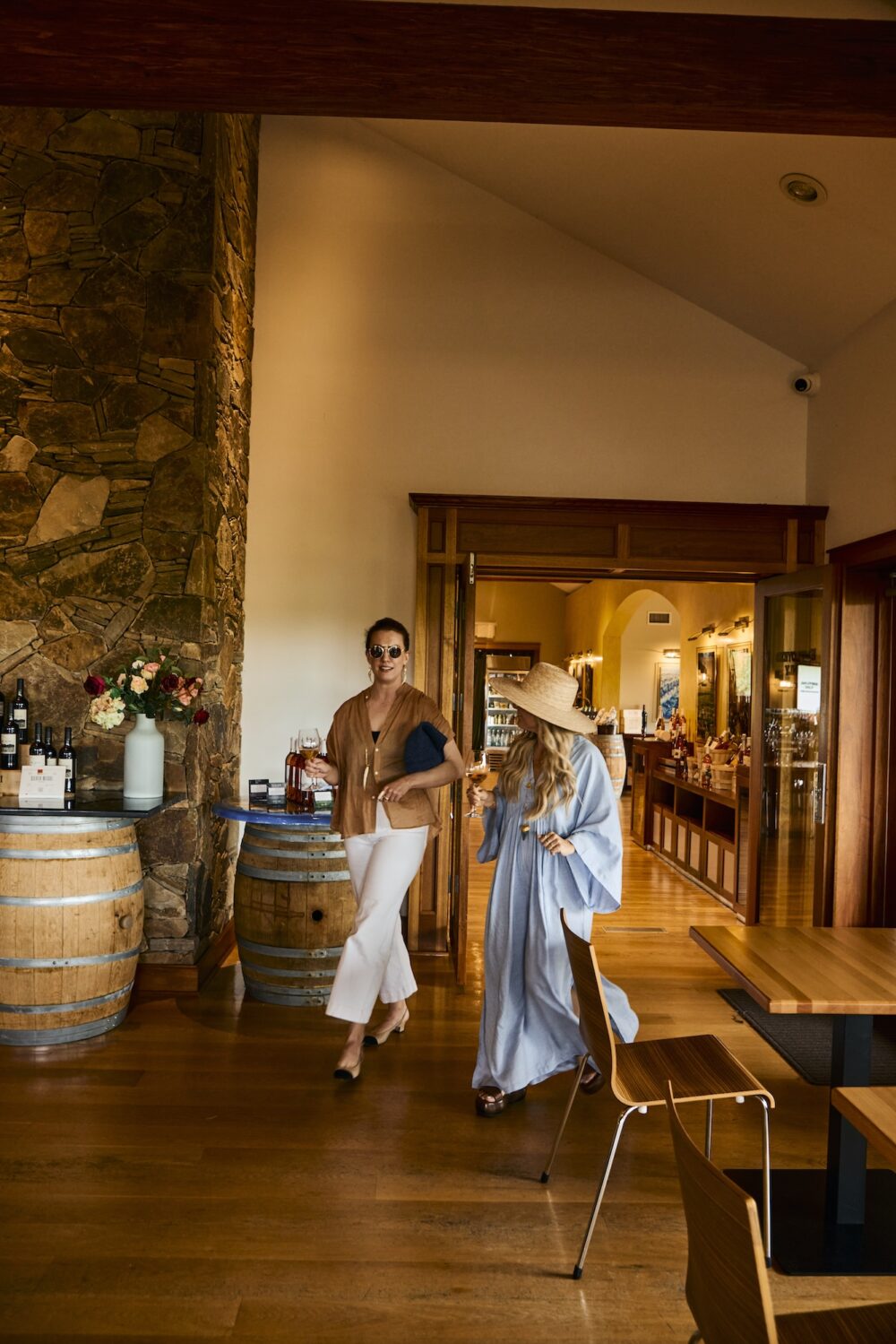 Two women walking with wine glasses at Macari Vineyards in Greenport, NY.