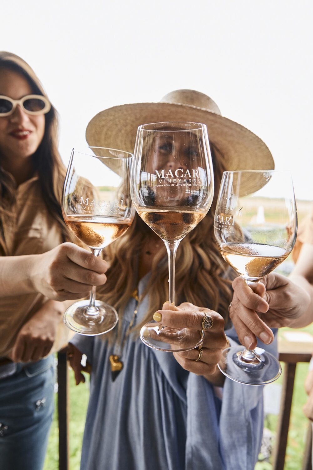 Three women toasting glasses of rosé from Macari Vineyards.