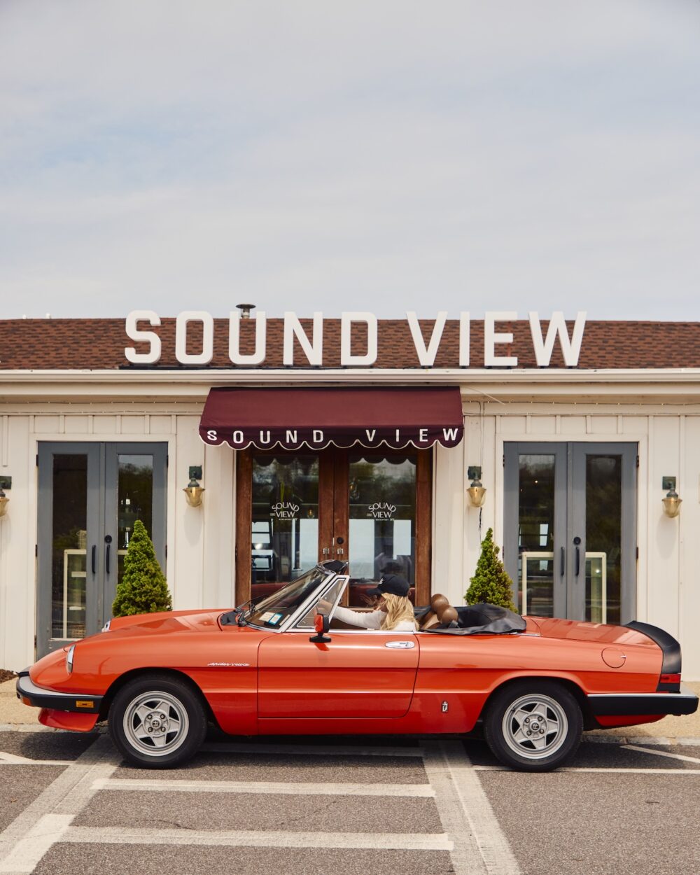 A vintage red car parked in front of Sound View Greeport, NY.
