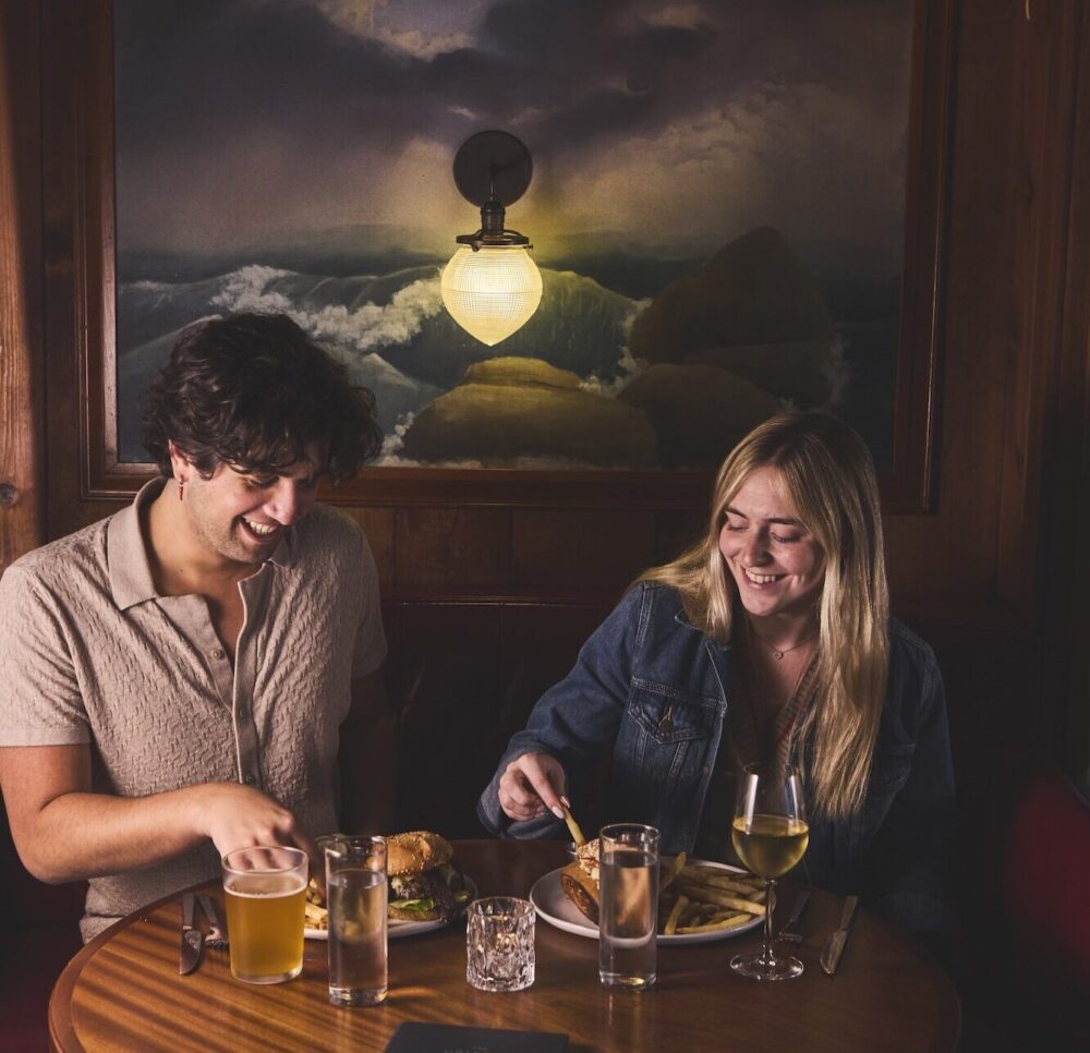 A couple having a meal and cocktails at The Piano Bar.