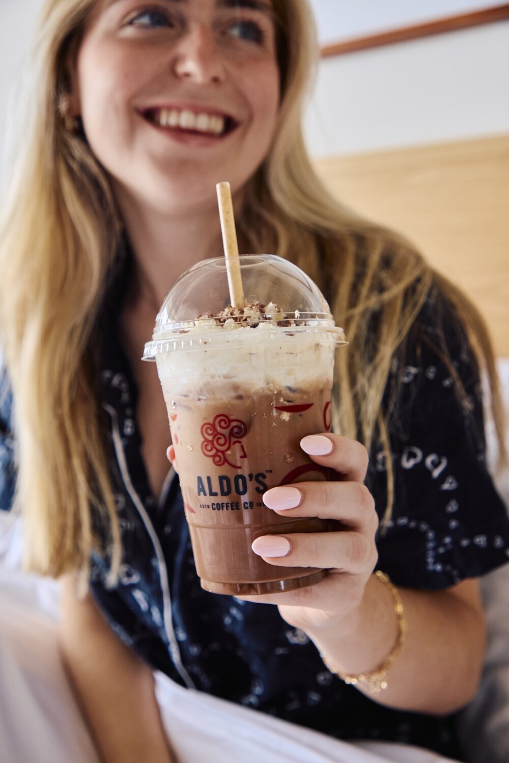 A woman having iced coffee in bed.