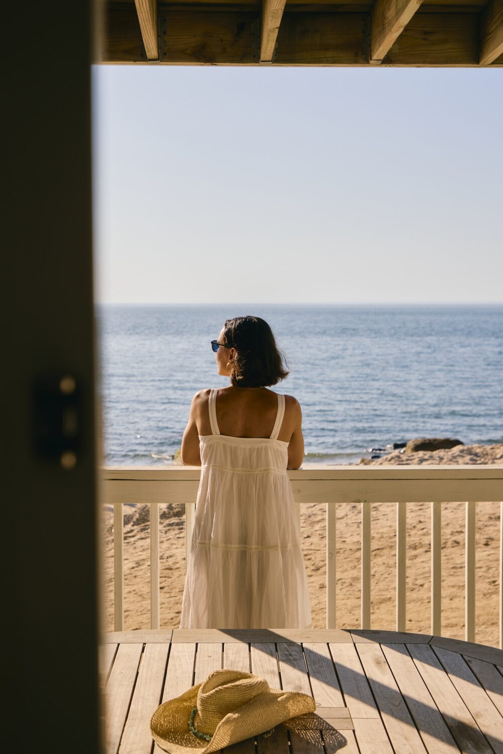 A woman looking out at the beach from her guest room patio.
