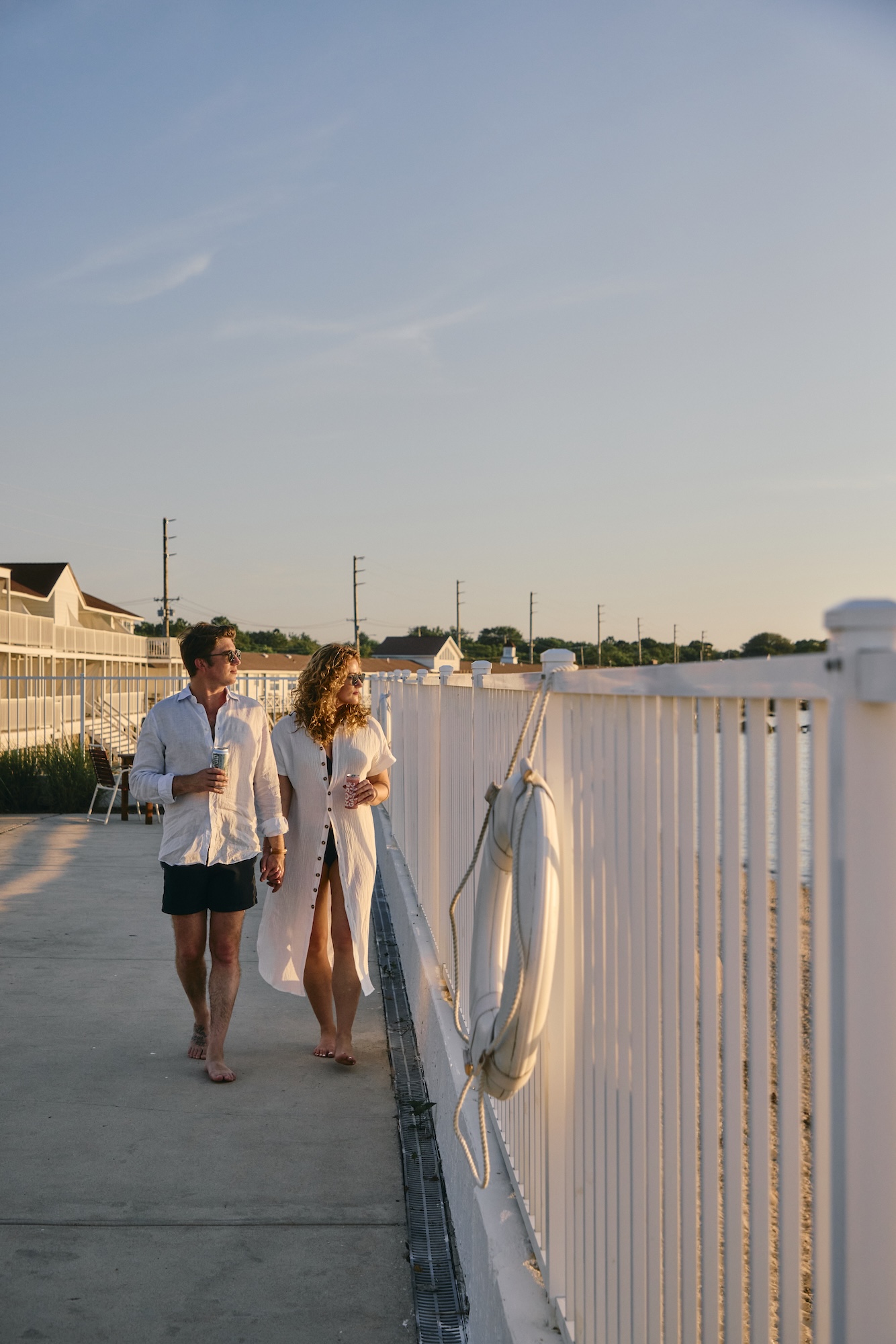 A couple walking along the water at sunset.