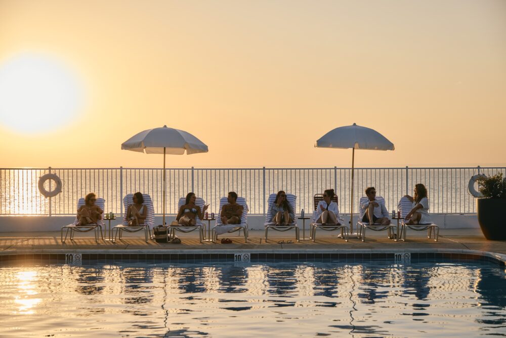 A row of people in lounge chairs talking at sunset.