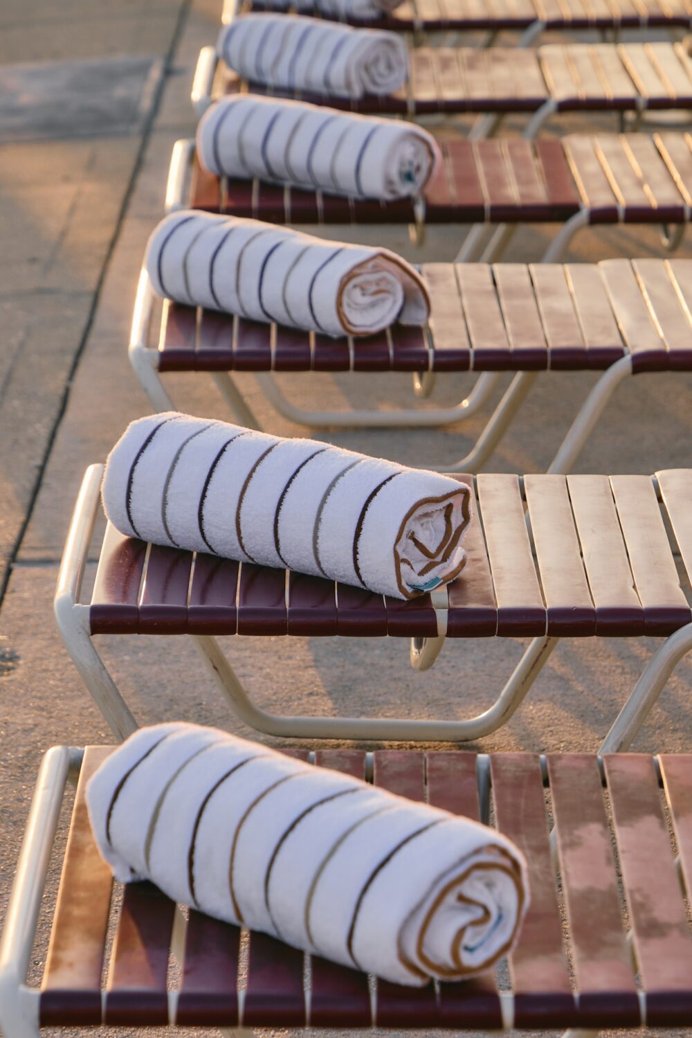 Towels on a row of red lounge chairs by the pool.