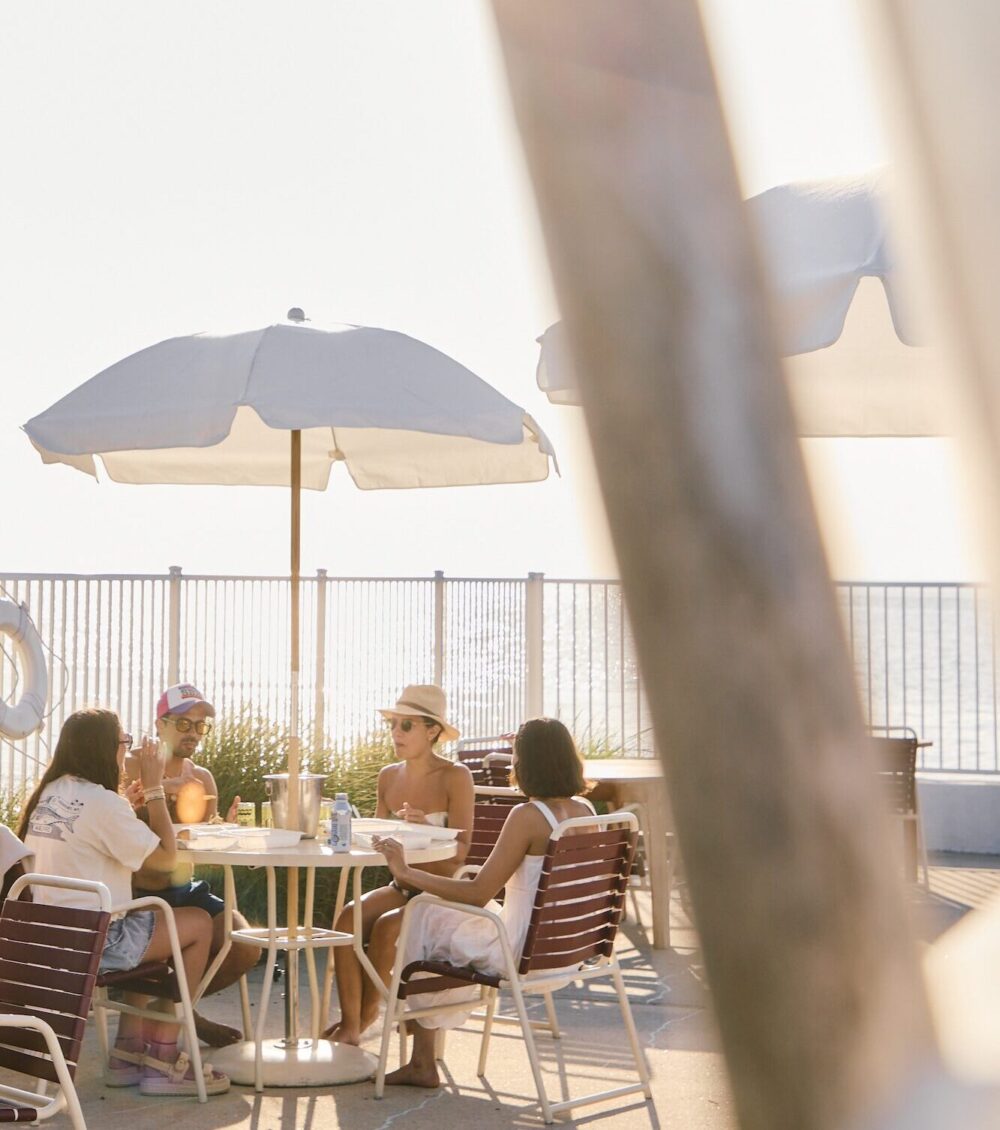 A group of friends eating outside by the pool.