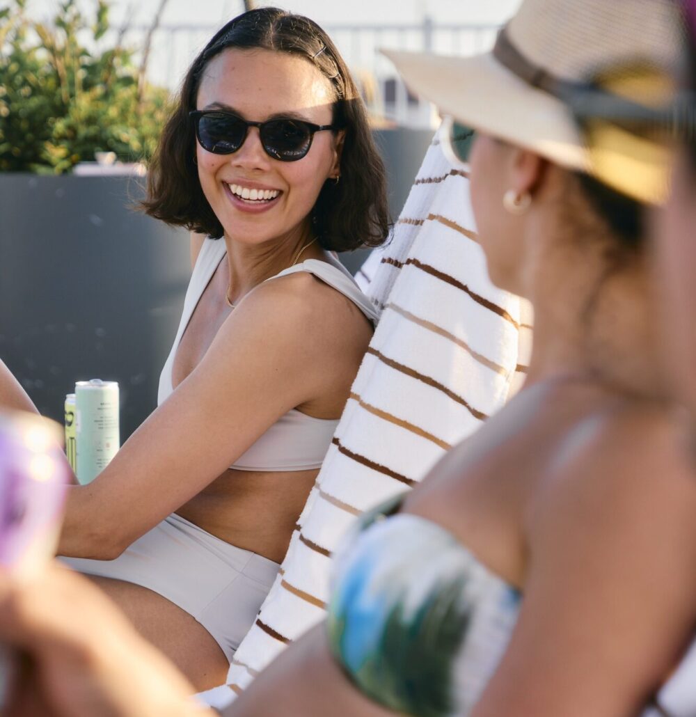 Two women smiling and talking by the pool.