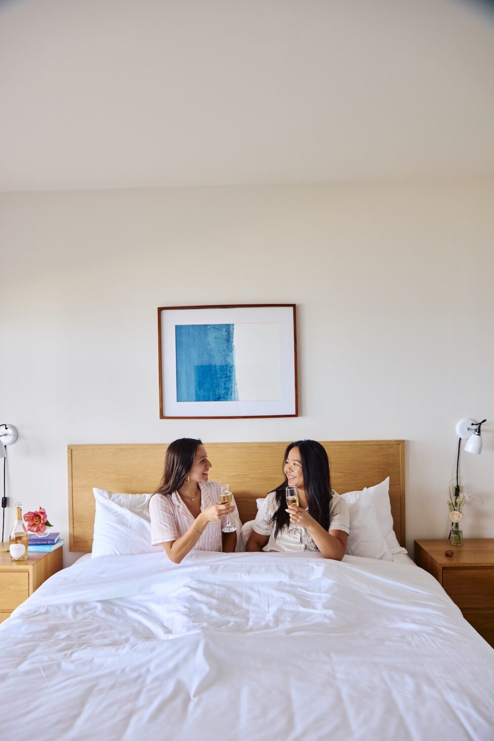 Two women having champagne in their pajamas in bed.