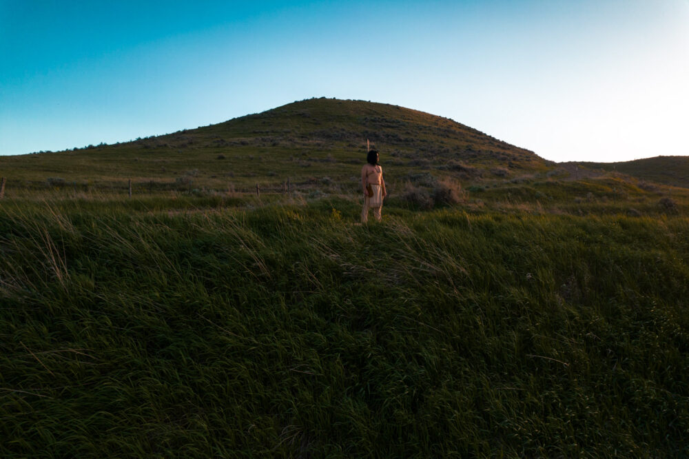 A photograph of a man standing on a grass hill, from a 2025 participation artist of Uncommon Art Residency in Jackson.