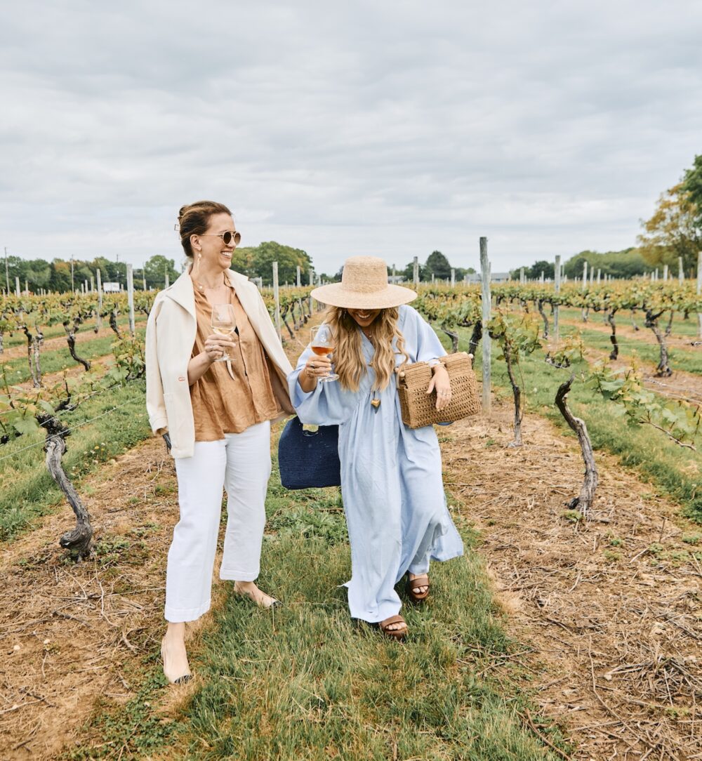 Two women having wine in a vineyard.